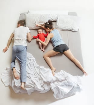 Top view of happy funny family with one newborn child in bedroom. Enjoying being together. Happy family in bed. Top view. Emotions concept. Morning after sleep. Family lifestyle. happy parents concept