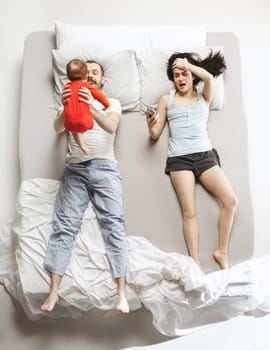 Top view of happy funny family with one newborn child in bedroom. Enjoying being together. Happy family in bed. Top view. Emotions concept. Morning after sleep. Family lifestyle. happy parents concept
