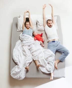 Top view of happy funny family with one newborn child in bedroom. Enjoying being together. Happy family in bed. Top view. Emotions concept. Morning after sleep. Family lifestyle. happy parents concept