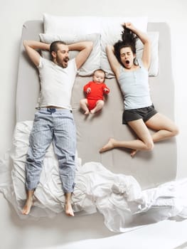 Top view of happy funny family with one newborn child in bedroom. Enjoying being together. Happy family in bed. Top view. Emotions concept. Morning after sleep. Family lifestyle. happy parents concept