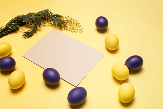 Beautiful easter table setting composition. A row of lilac and yellow color eggs on yellow background. Happy Easter greeting card. Top view, copy space.