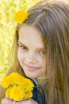 Close-up portrait of eight-year-old girl with dandelions in hands