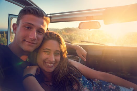 Happy couple in a car enjoying sunset.