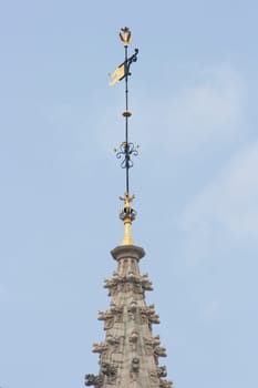 Spire with gold-trimmed weathercock, and blue sky in background
