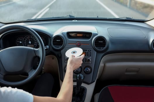Woman inserting CD Audio while she is driving. Cause of Distracted Driving Accidents concept. Inside car view