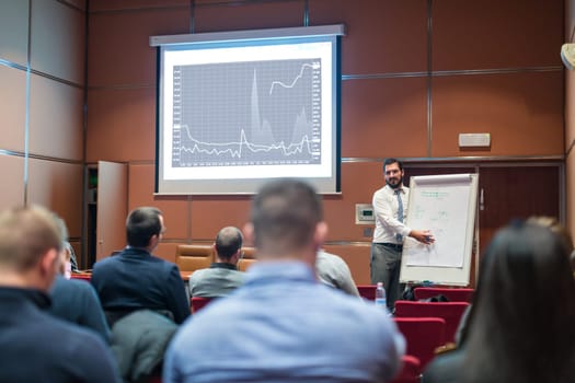 Public Speaker Giving a Talk at Business Meeting. Audience in the conference hall. Skilled coach answers questions of participants of business training. Business and Entrepreneurship concept.