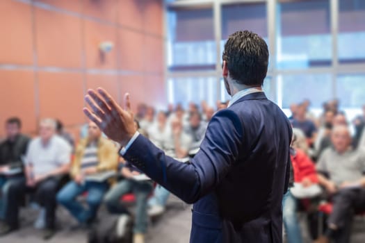 Rear view of speaker giving a talk at business meeting. Audience in the conference hall. Business and Entrepreneurship concept.