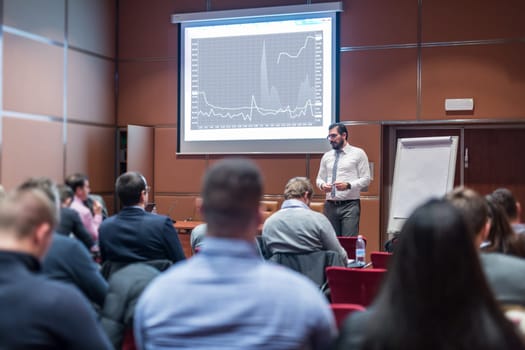 Public Speaker Giving a Talk at Business Meeting. Audience in the conference hall. Skilled coach answers questions of participants of business training. Business and Entrepreneurship concept.