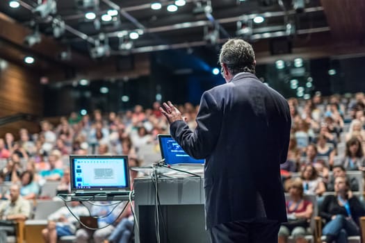 Speaker giving a talk on corporate business conference. Unrecognizable people in audience at conference hall. Business and Entrepreneurship event.