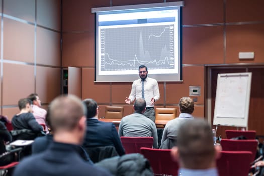 Public Speaker Giving a Talk at Business Meeting. Audience in the conference hall. Skilled coach answers questions of participants of business training. Business and Entrepreneurship concept.