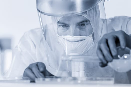 Life scientist researching in bio hazard laboratory. Focused life science professional working on experiment in high protection degree work laboratory. Healthcare and biotechnology.