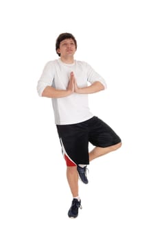 A young handsome man in shorts and t-short standing on one leg with hands.folded, meditating, isolated for white background.