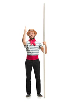 Choose me. Caucasian funny bearded man in traditional gondolier costume and hat with paddle standing and posing at studio isolated on white background. Smiling young man. Human emotions, facial expression concept