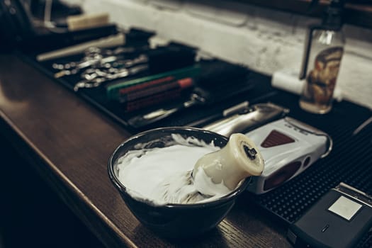 Barber shop tools on the table. Close up view shaving foam. Barber shop concept. Shaving machine, comb, scissors and different items on the table in the barber shop.