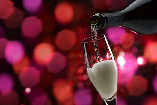 Pouring sparkling white wine into a wineglass, wine tasting and celebration concept