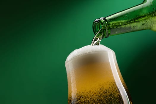 Pouring fresh beer from a bottle into a glass, alcoholic drinks and celebration concept