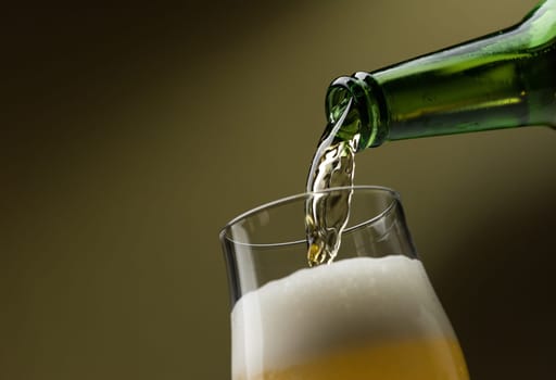 Pouring fresh beer from a bottle into a glass, alcoholic drinks and celebration concept