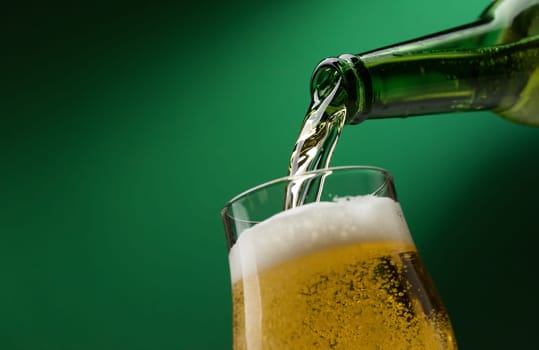 Pouring fresh beer from a bottle into a glass, alcoholic drinks and celebration concept
