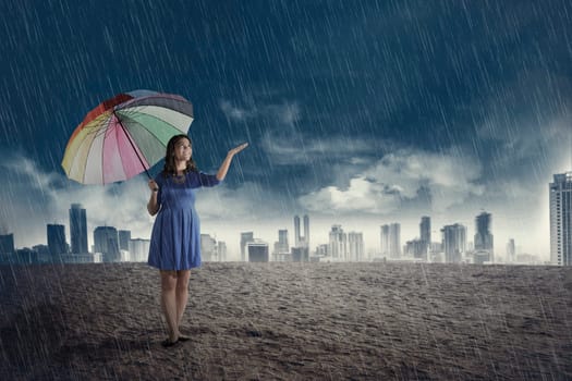 Happy asian woman with umbrella when rain over dark sky background