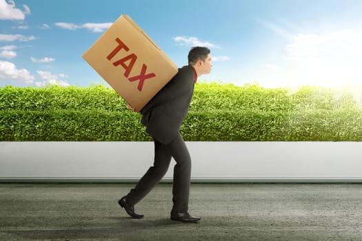 Young asian businessman carrying heavy box of TAX. Taxation concept