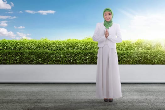 Young asian muslim woman in headscarf praying at outdoor