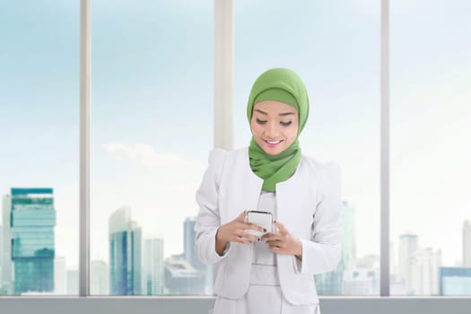Beautiful asian muslim woman with mobile phone inside the building