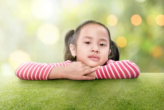 Happy asian girl lean on the green grass at outdoor