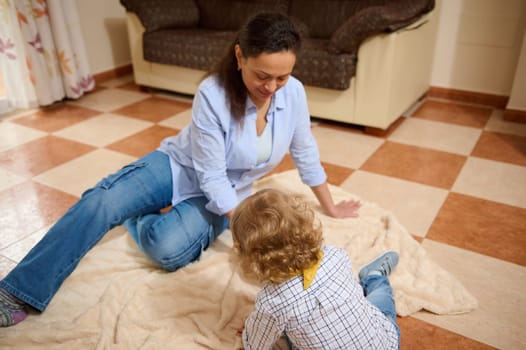 Mother and child sitting on a cozy floor bonding indoors, surrounded by comfortable decor, embodying maternity sentiments and shared joy.