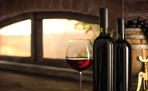 Red wine glass, bottles and barrel next to the  cellar window: traditional wine making concept