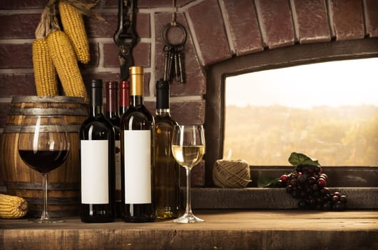Wine bottles, wineglasses, barrels next to the cellar window and beautiful panoramic view of countryside vineyards: winemaking and wine culture concept