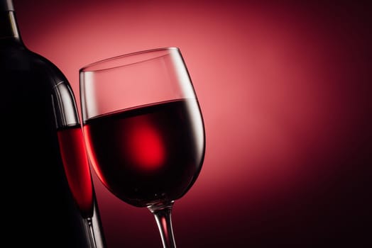Luxury wine tasting event and celebration: excellent red wine bottle and full wine glass close up on red background