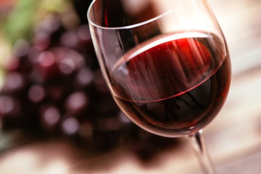 Italian red wine tasting and wine culture: wine glass and grape on a rustic wooden table