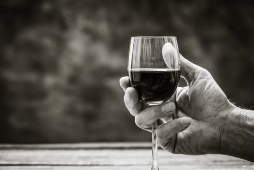 Senior wine expert tasting a glass of red wine in the cellar, hand close up, wine tradition and culture concept
