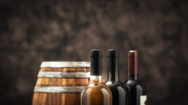 Expensive wine bottles collection and wooden barrel in the cellar, wine tasting and production concept