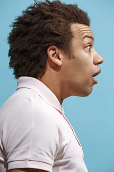 Wow. Attractive male half-length front portrait on blue studio backgroud. Young emotional surprised bearded man standing with open mouth. Human emotions, facial expression concept. Trendy colors. Profile