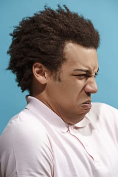 Reject, rejection, doubt concept. Doubtful afro man with thoughtful expression making choice. Young emotional man. Human emotions, facial expression concept. Front . Studio. Isolated on trendy blue