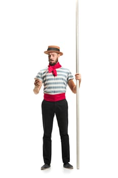 Caucasian funny bearded man in traditional gondolier costume and hat with paddle standing with mobile phone at studio isolated on white background. young man. Human emotions, facial expression concept