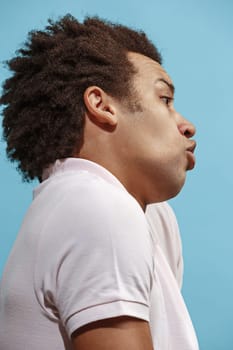 Argue, arguing concept. Beautiful male half-length portrait isolated on blue studio backgroud. Young emotional surprised afro man Human emotions, facial expression concept. Profile view