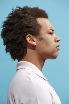 I am tired of everything. Sad man. Boring, dull, tedious concept. Young afro emotional man. Human emotions, facial expression concept. Studio Isolated on trendy blue background. Profile