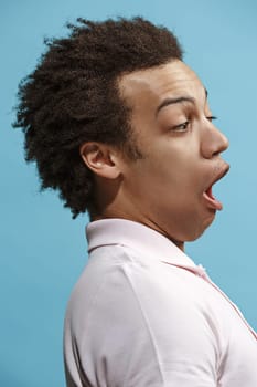 Wow. Attractive male half-length front portrait on blue studio backgroud. Young emotional surprised bearded man standing with open mouth. Human emotions, facial expression concept. Trendy colors. Profile