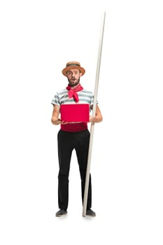 Caucasian funny bearded man in traditional gondolier costume and hat with paddle standing with mobile phone at studio isolated on white background. young man. Human emotions, facial expression concept
