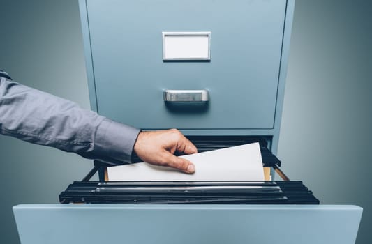 Office clerk searching for files in the filing cabinet, data storage and archives concept