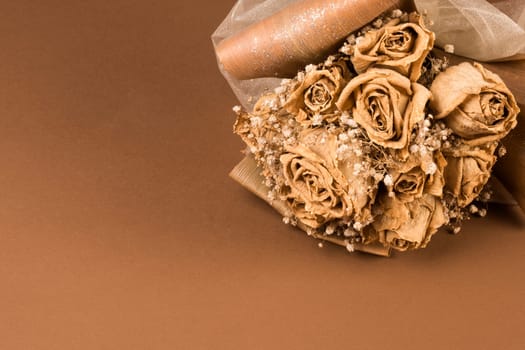 Dried wedding bouquet of roses on brown background.