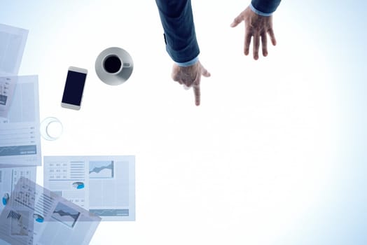 Businessman pointing to a white desktop with financial reports and blank copy space, top view