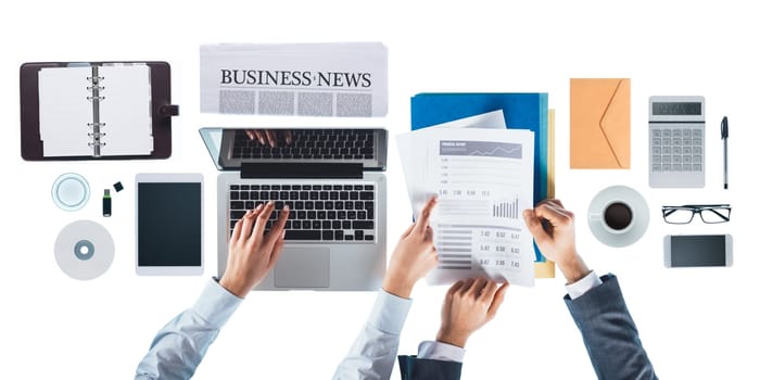 Business people working together at office desk and checking financial report, she is pointing at a number
