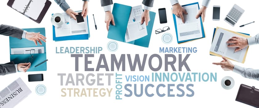 Business text concepts and business team working at office desk during a meeting, hands top view, unrecognizable people, strategy and teamwork concept