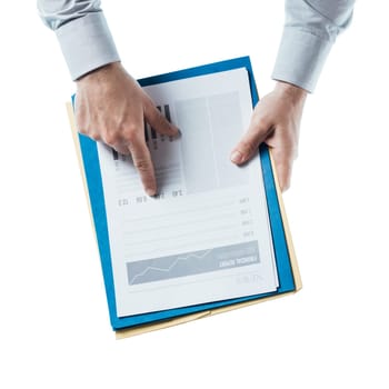 Businessman holding a financial report and pointing at at number, hands close up, top view
