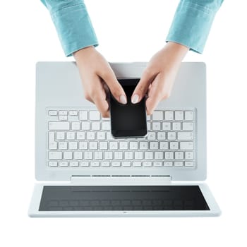 Woman using a touch screen smart phone and a laptop on white background, hands close up, top view