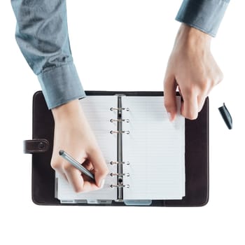 Female assistant writing schedule in a open planner pages hands close up, top view
