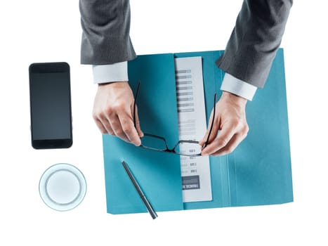 Businessman at desk holding glasses on white background, hands close up top view